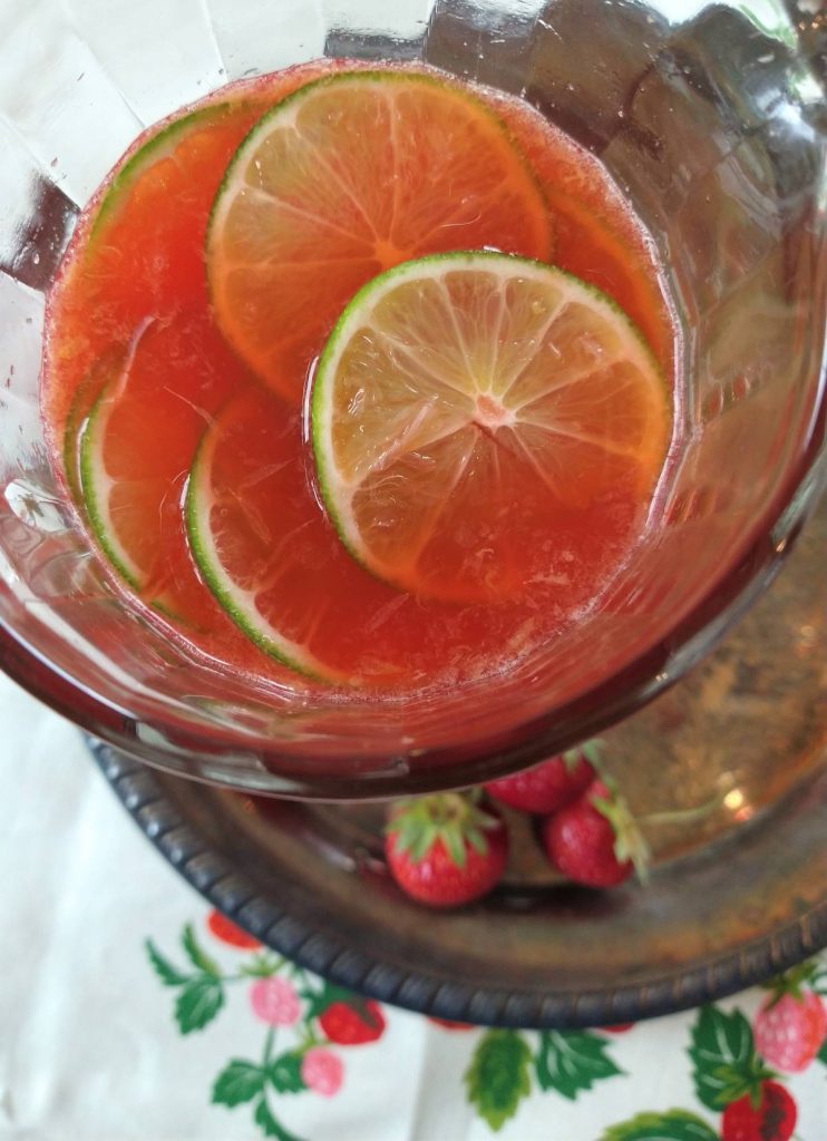 Strawberry Summer Punch with limes in a glass pitcher