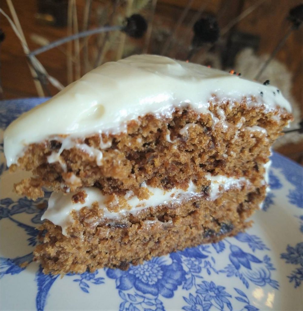 prune spice cake with white frosting on a blue and white china plate