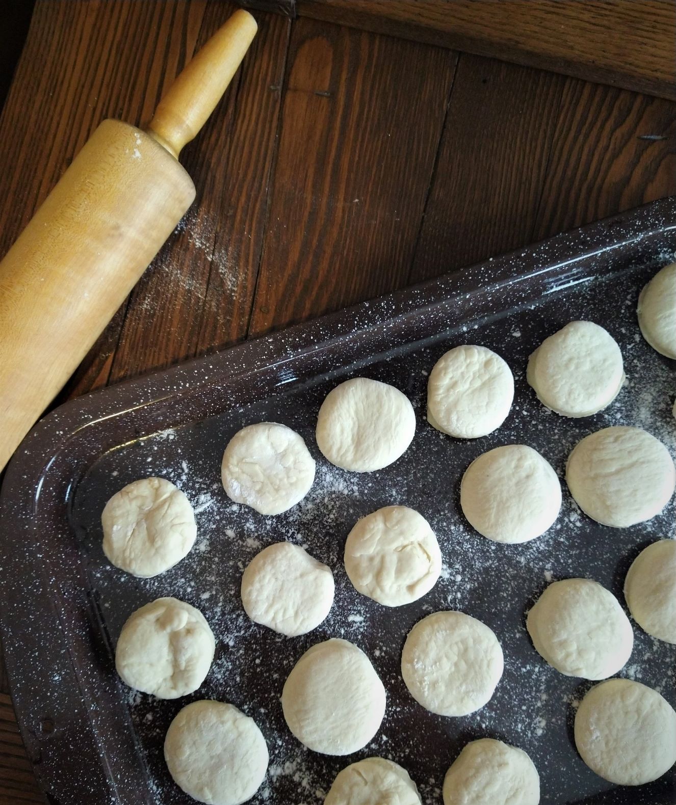 mini no-bake rolls are lined up on baking sheet ready for grilling with a rolling pin nearby