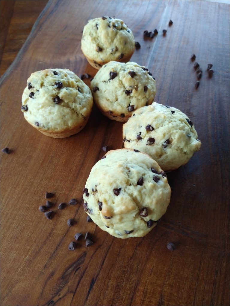 chocolate chip muffins on a board surrounded by chocolate chips