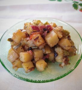 cooked potatoes and bacon on a green plate