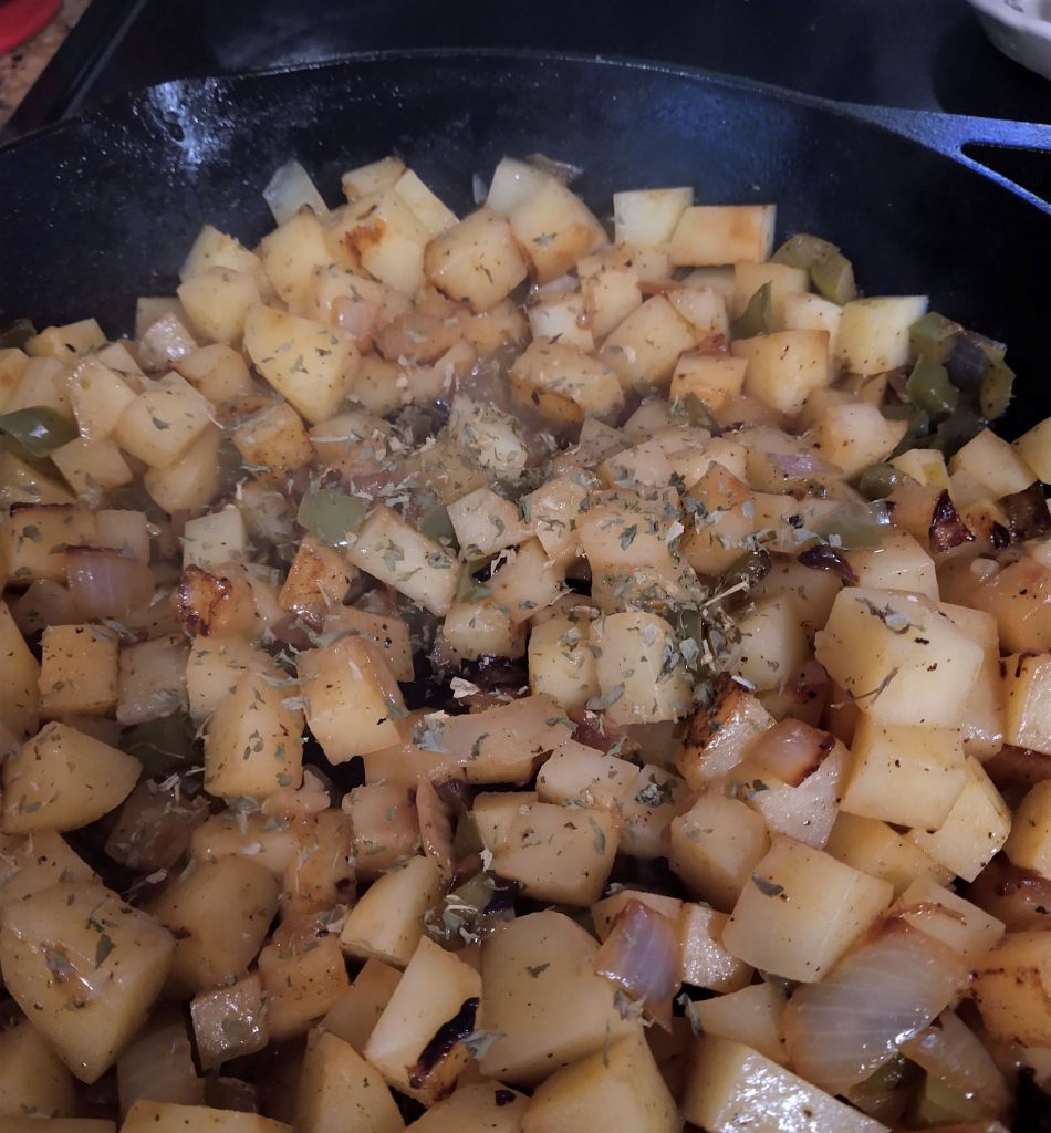 cubed potatoes with herbs cooking in a cast iron skillet