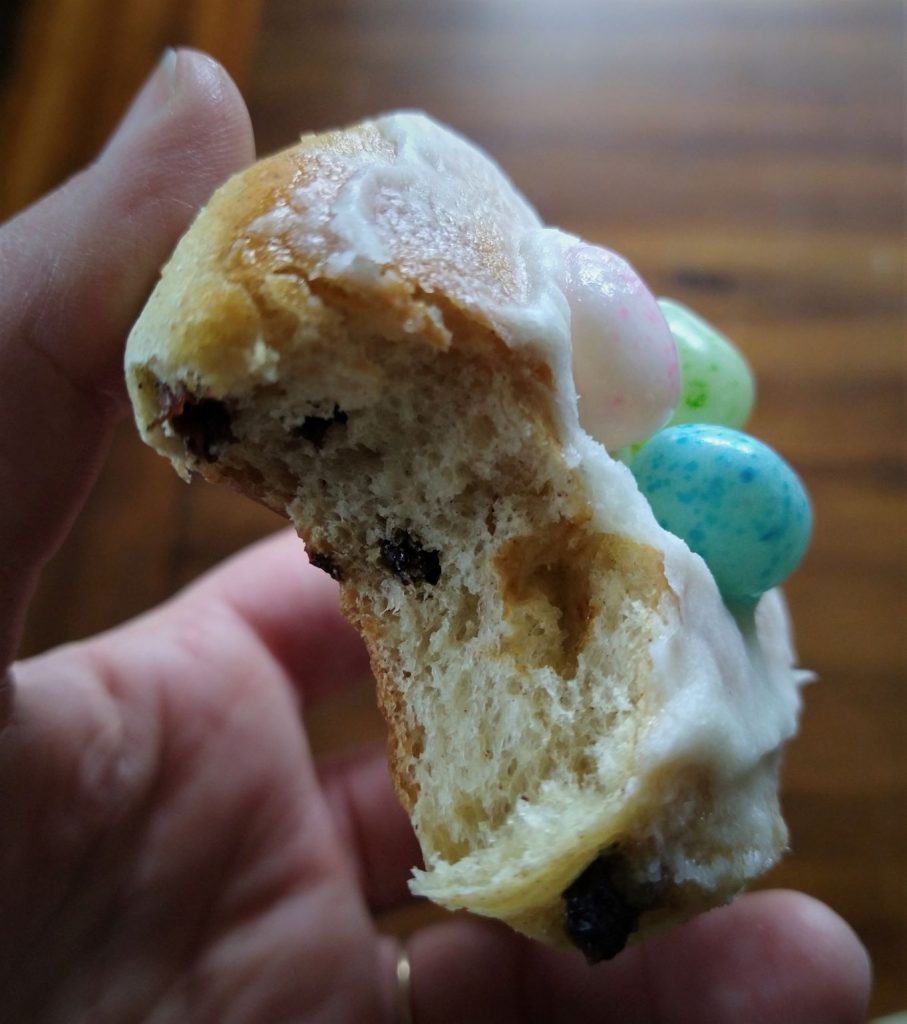 hand holding a sweet roll with jelly beans on top