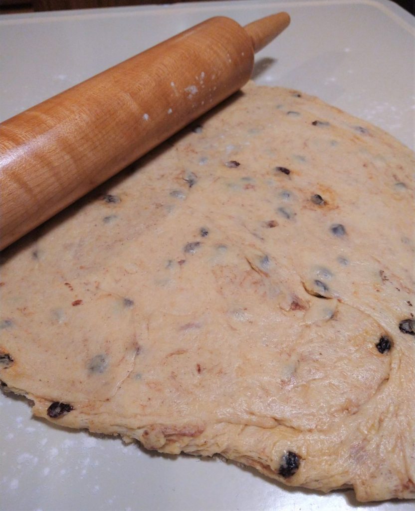 dough with raisins rolled flat with a rolling pin
