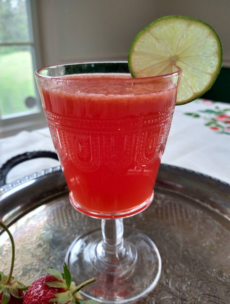 glass goblet of strawberry summer punch with strawberries on a silver platter