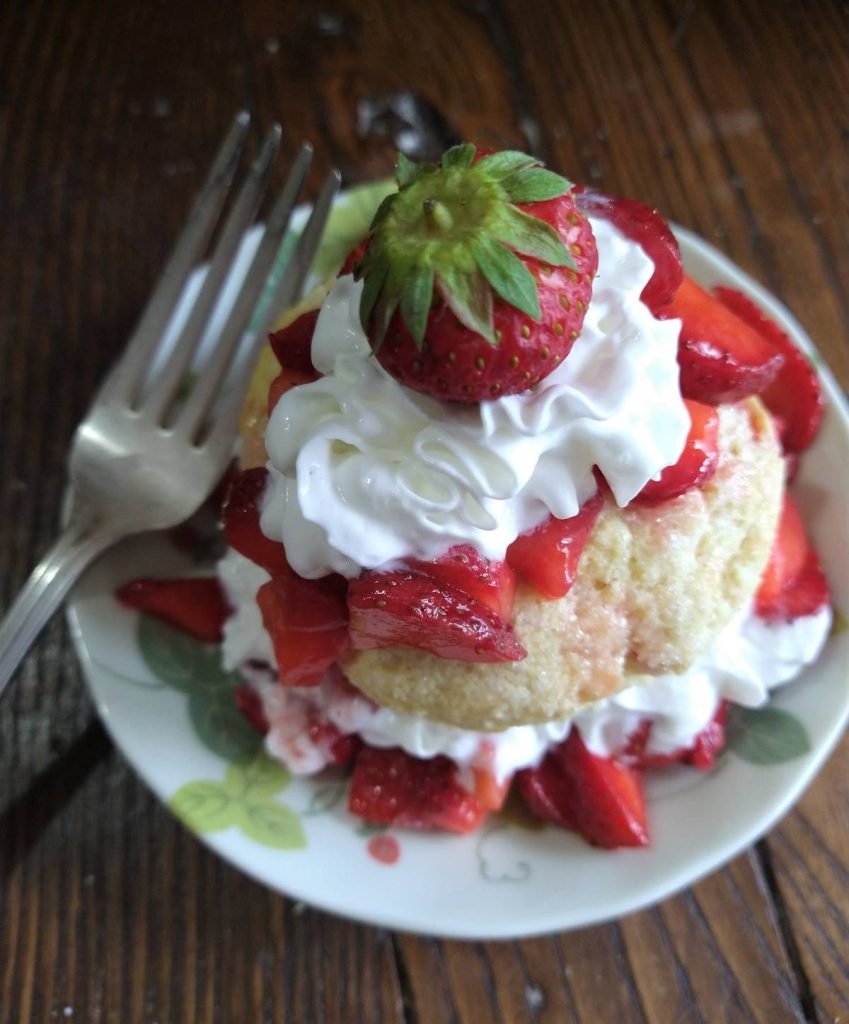 citrus strawberry shortcake with whipped cream and a fork resting on the plate
