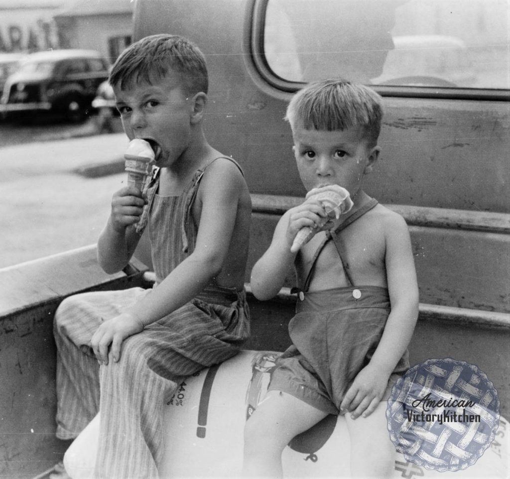 black and white photo of two boys in overalls eating ice cream cones in the back of a pickup truck
