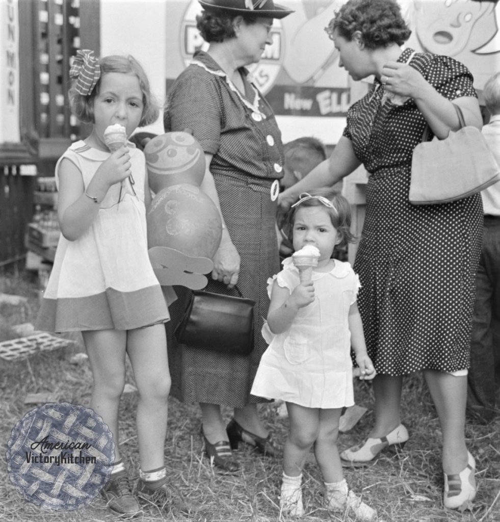 black and white photo of two girls eating ice cream cones at a fair