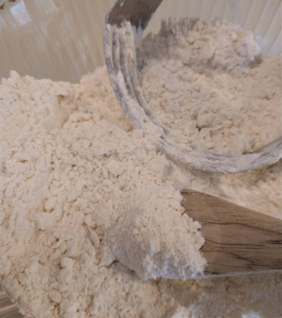 bowl of flour mixture, wooden spoon and pastry blender