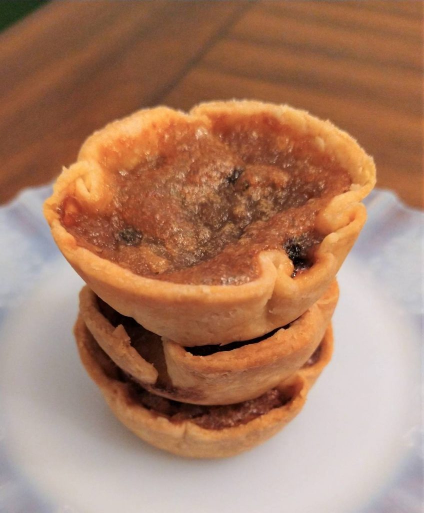 a stack of three maple butter tarts on a white glass plate