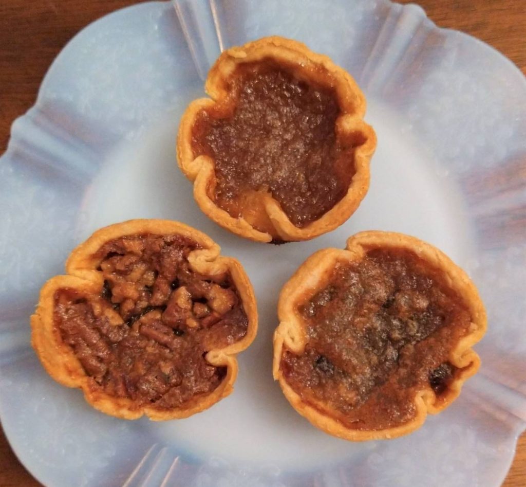 three maple butter tarts on a white glass plate