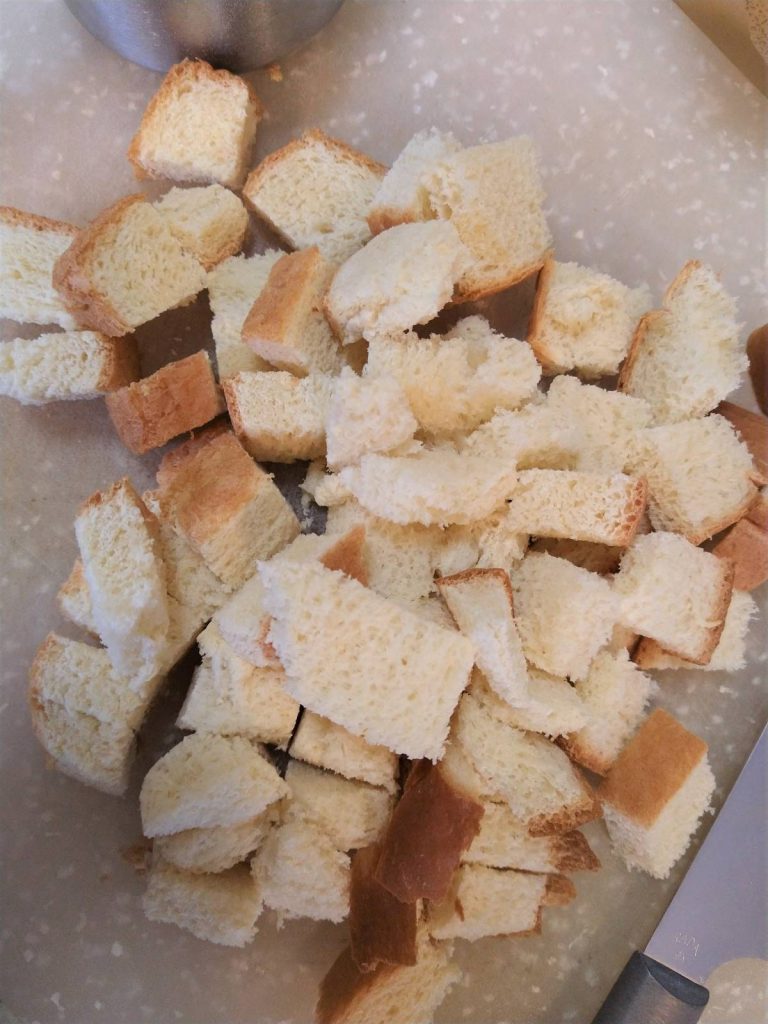 white bread cubes sitting on a white cutting board