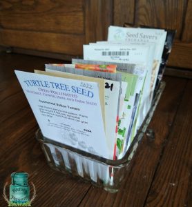 a vintage glass dish full of seed packets on a wooden table