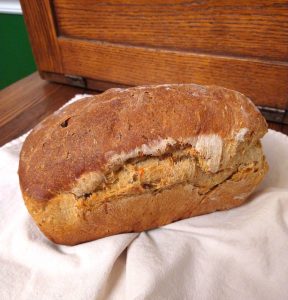 a loaf of carrot raisin bread sits in a cloth-covered basket